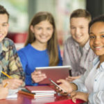 four teenagers sitting at a table