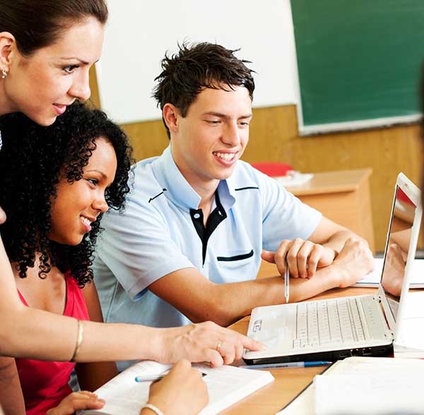 teacher helping students use computer