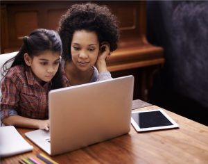 Mother helping daughter at laptop